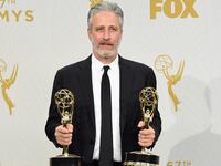 A picture of Jon Stewart holding two Emmys.