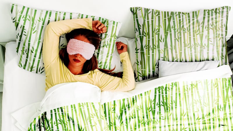 Woman laying in bed with sheets with bamboo patterns on it