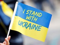 A person holds a Ukrainian flag as people attend a rally to mark the one-year anniversary of Russia’s invasion of Ukraine, in Paris, France, Feb. 25, 2023.