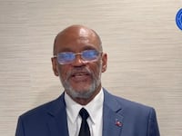 Ariel Henry, wearing a suit, addresses his country in a video message.