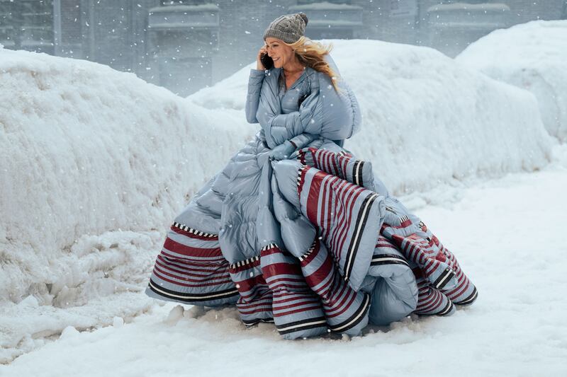 A still showing Carrie Bradshaw in a large puffer coat in And Just Like That.