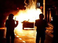Riot police stands next to a burning police vehicle, near the scene of a suspected stabbing that left few children injured in Dublin, Ireland, November 23, 2023.