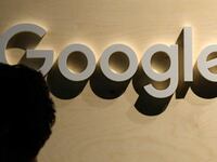 A woman passes the logo from the web search engine provider Google