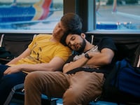 Jacob Roberts and Ben Treviño lean on each other on seats in an airport in a still from ‘Rent Free’
