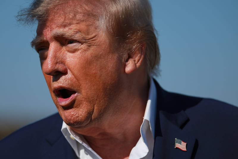 President Donald Trump's exposed neck shows his dramatic makeup line as he stops to speak to members of the press as he walks to board Air Force One on October 27, 2026 at Joint Base Andrews, Maryland.