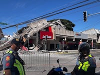 TOPSHOT - Police gather in front of a collapsed Jollibee fast food restaurant after an 7.8 magnitude earthquake in General Santos City on June 8, 2026. A 7.8-magnitude earthquake that struck the southern Philippines on June 8 killed at least one person and collapsed buildings, police said, as the disaster sparked tsunami warnings across the region. (Photo by Edwin Espejo / AFP via Getty Images)