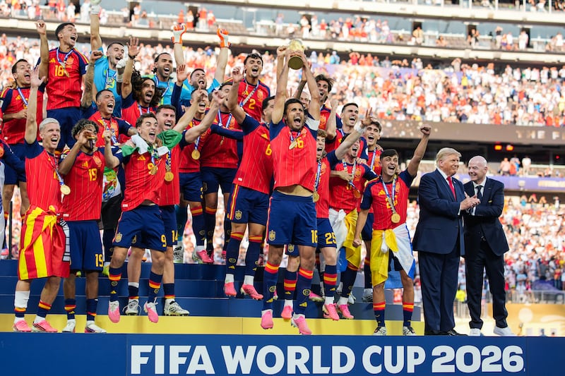 EAST RUTHERFORD, NEW JERSEY - JULY 19: US President Donald Trump and FIFA President Gianni Infantino stand on stage as Rodri #9 of Spain raises the FIFA World Cup Winner’s Trophy with his teammates after they defeated Argentina in the FIFA World Cup 2026 Final at New York New Jersey Stadium on July 19, 2026 in East Rutherford, New Jersey. Spain defeated reigning World Cup champions Argentina, who were led by Lionel Messi, with the lone goal coming from Ferran Torres #7 in the 106th minute of extra time. (Photo by Andrew Harnik/Getty Images)