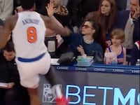 A screenshot shows New York Knicks player OG Anunoby barreling towards actress Anne Hathaway, seated in the front row of Madison Square Garden, after he attempted a steal.