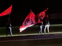 A video still shows masked protestors waving flags with Nazi insignia outside American Legion Post 141 in Howell, MI.