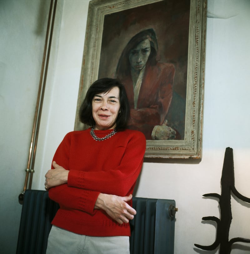 The late American author Patricia Highsmith poses in front of her portrait at her home in 1970.