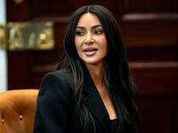 Kim Kardashian, wearing black, speaks at a meeting table.