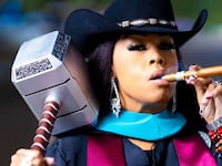 A close up portrat of Candice Matthews smoking a cigar and holding a Viking hammer