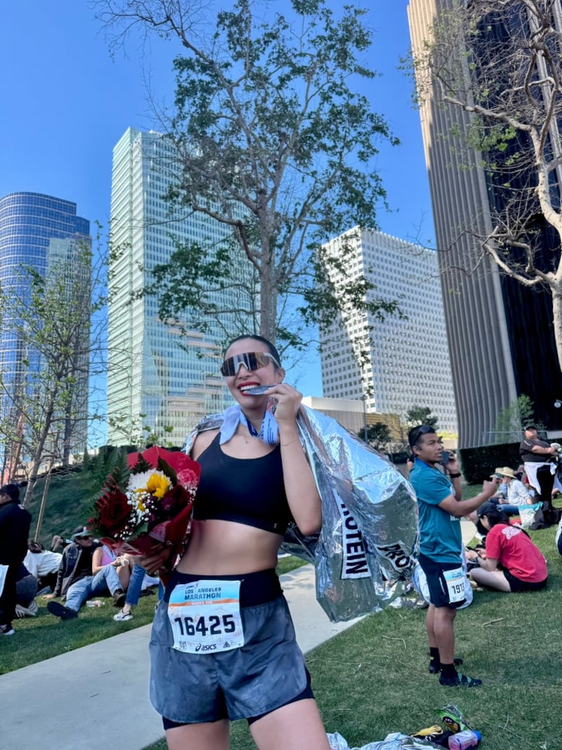Nadya Okamoto poses for a picture while biting her finisher’s medal for the Los Angeles Marathon.