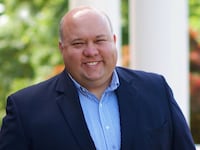 Bubba Copeland, wearing a button-up shirt and blazer, smiles in a headshot.