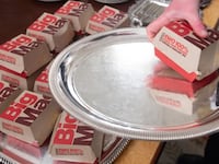 A White House usher plates Big Macs from McDonalds, some of the fast food the US president purchased for a ceremony honoring the 2018 College Football Playoff National Champion Clemson Tigers in the State Dining Room of the White House in Washington, DC, January 14, 2019. - US President Donald Trump says the White House chefs are furloughed due to the partial government shutdown. (Photo by SAUL LOEB / AFP) (Photo credit should read SAUL LOEB/AFP via Getty Images)