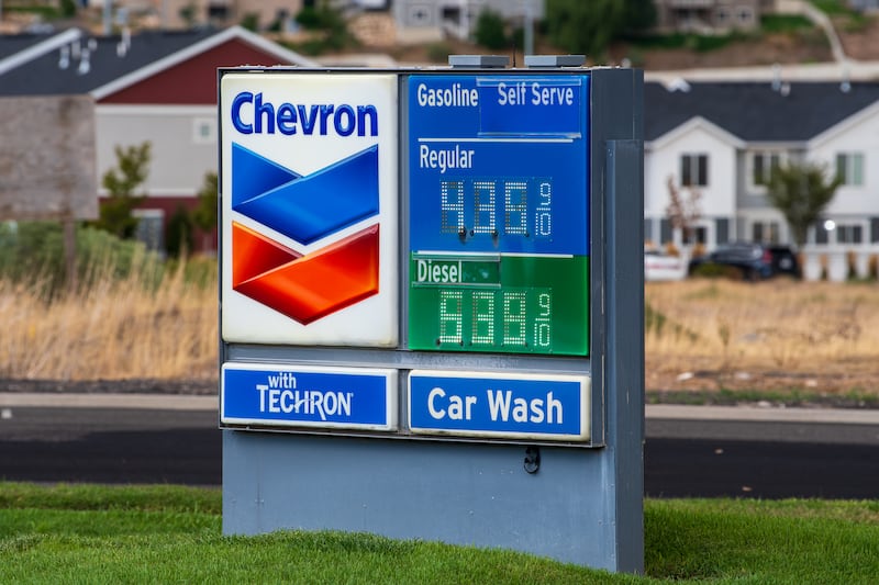 A close-up view shows a Chevron roadside fuel price sign standing near a roadway in Santaquin, Utah, United States, on August 30, 2026. The sign displays current retail pricing for self-serve regular gasoline at $4.35 and diesel at $5.39 per gallon against a background of residential housing.
