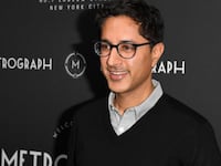 Maulik Pancholy poses in front of an advertising board.