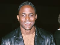 Wayne Brady wearing a black leather jacket and brown sweater in 2000.