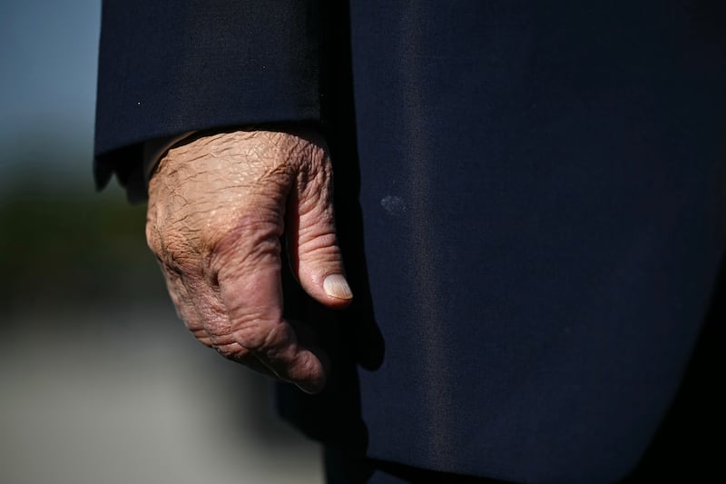 President Donald Trump's hand is seen covered in makeup as he speaks to members of the press before boarding Air Force One at Joint Base Andrews, Maryland on October 27, 2026.