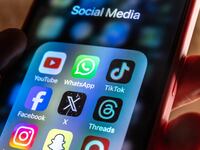 In this photo illustration, A man holds a smartphone iPhone screen showing various social media apps including YouTube, TikTok, Facebook, Threads, Instagram and X on March 13, 2024 in Bath, England.