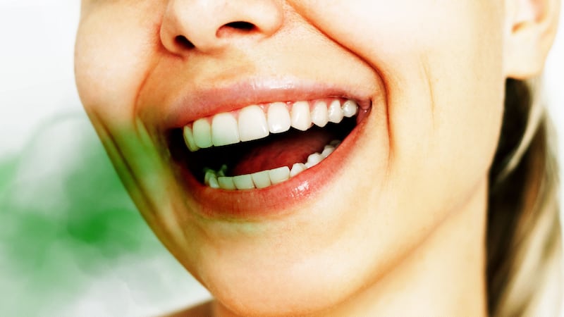 Woman smiling with an open mouth and straight teeth with a green odor blob coming out of her mouth showing bad breath