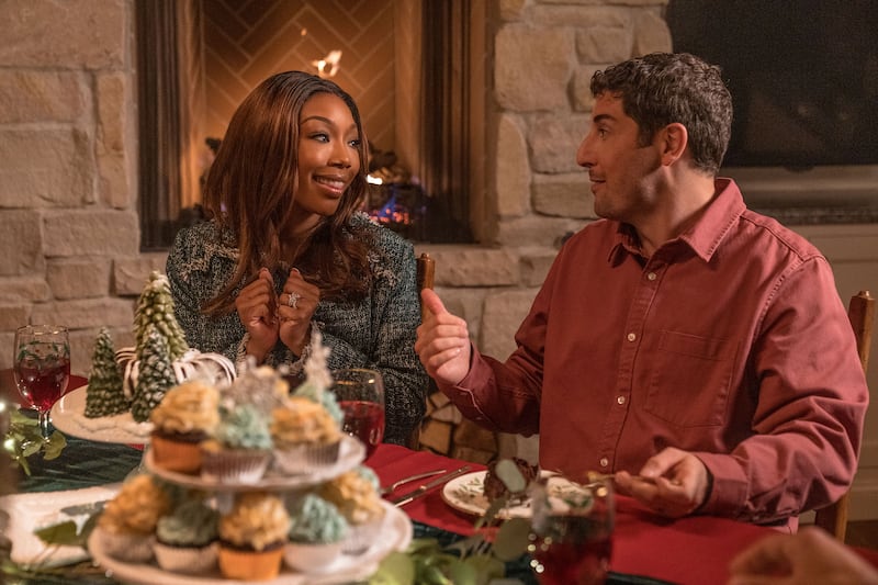 Brandy Norwood and Jason Biggs sit next to each other at a dinner table in a still from ‘Best Christmas Ever’