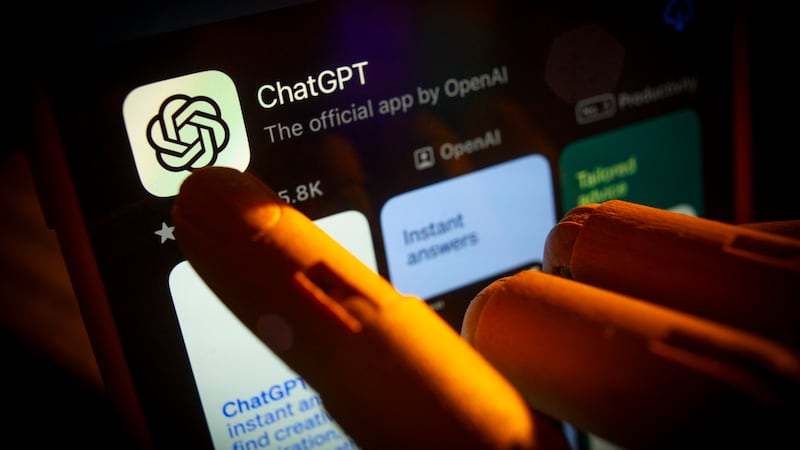 An artificial hand is seen pointing a finger onto a mobile phone screen displaying the Apple App Store with the Chat GPT app in this photo illustration on 29 October, 2023 in Warsaw, Poland.