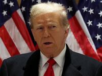 Donald Trump stands in front of American flags.