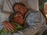 Matt Bomer and Jonathan Bailey hold each other in a bed in a still from ‘Fellow Travelers’