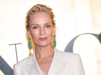 Actress Uma Thurman wearing minimal makeup and a white suit jacket