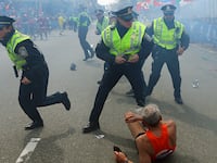 Police officers with their guns drawn hear the second explosion down the street. The first explosion knocked down 78-year-old US marathon runner Bill Iffrig at the finish line of the 117th Boston Marathon.