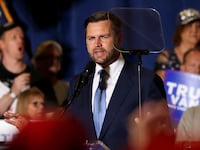 J.D. Vance looks at a teleprompter while speaking on stage.