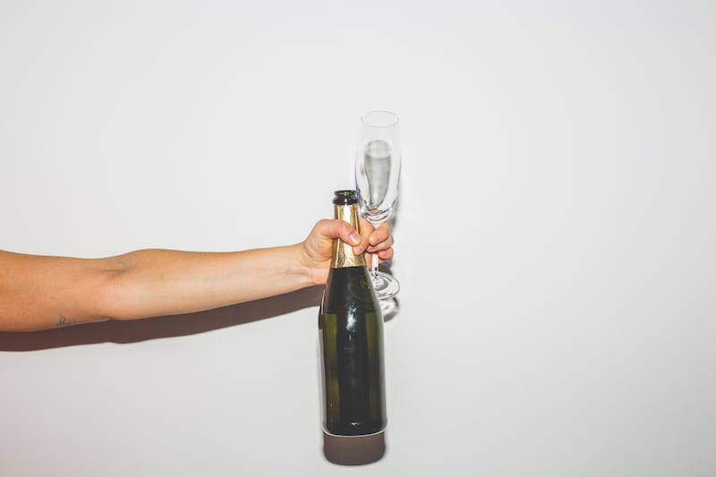 Hand holding a bottle and a glass of Champagne