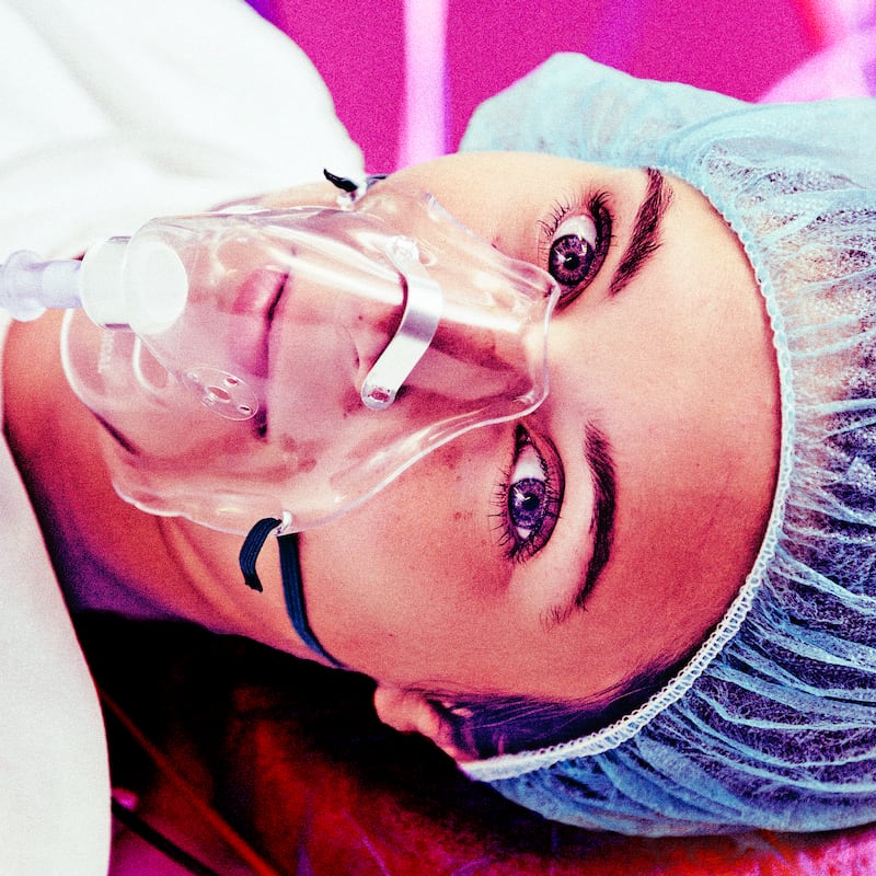 A photo illustration of a patient with respiratory mask awake on operating room table.