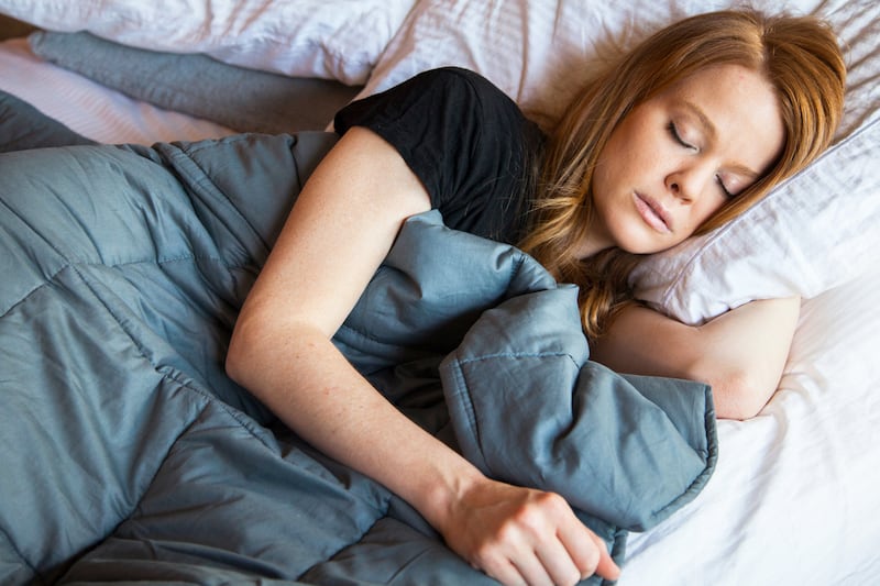 A woman taking a nap with a weighted blanket.