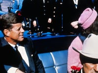 US President John F Kennedy (left), First Lady Jacqueline Kennedy (in pink), and Texas Governor John Connally ride in a motorcade from the Dallas airport into the city.