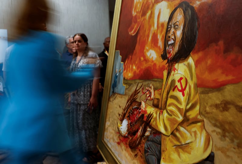 A person walks past a grotesque satirical painting of Vice President Kamala Harris on display at the Moms for Liberty "Joyful Warriors" conference in Washington, D.C. on August 30, 2024.