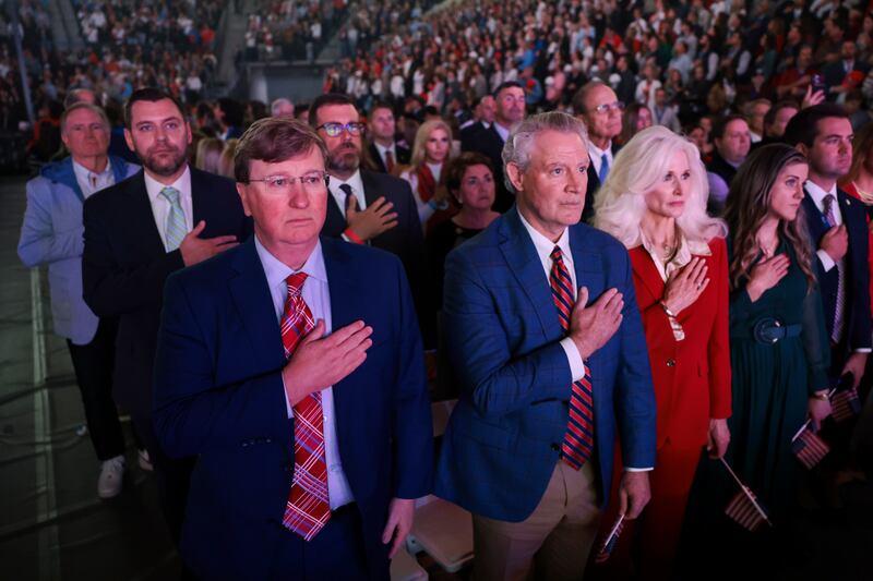 Governor of Mississippi, Tate Reeves, (L) stands with other attendees during the national anthem at a Turning Point USA event