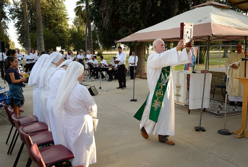 Deacon Ed Valdez of St. Anthony's of Padua carries the Bible during a mass held at Kearney Park as part of the Roman Catholic Diocese of Fresno's 50th anniversary conducted through their mobile chapel on September 19, 2017, in Fresno, Calif.