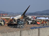 TOPSHOT - Firefighters and rescue personnel work near the wreckage of a Jeju Air Boeing 737-800 series aircraft after the plane crashed and burst into flames at Muan International Airport in South Jeolla Province, some 288 kilometres southwest of Seoul on December 29, 2024. A Jeju Air plane carrying 181 people from Bangkok to South Korea crashed on arrival December 29, colliding with a barrier and bursting into flames, with only two survivors rescued so far and 120 confirmed dead. (Photo by JUNG YEON-JE / AFP) (Photo by JUNG YEON-JE/AFP via Getty Images)