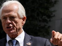 Peter Navarro, wearing a suit, speaks to reporters after a pre-trial conference in Washington.