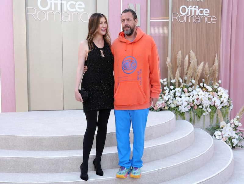 Jackie Sandler and Adam Sandler wear contrasting outfits as they attend the world premiere of Netflix's "Office Romance" in 2026.