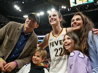 Caitlin Clark #22 of the Indiana Fever poses for a photo with Ashton Kutcher and Mila Kunis after defeating the Los Angeles Sparks