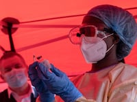 TOPSHOT - A nurse wears protective medical clothing and prepares a syringe by drawing a dose from a vaccine vial during the launch of an Ebola trial vaccination campaign at Mulago Referral Hospital in Kampala on February 3, 2025. Uganda started an Ebola Sudan virus vaccination trial on February 3, 2024, four days after an outbreak was confirmed, the WHO announced, beginning with those deemed at highest risk of the disease. (Photo by Badru Katumba / AFP) (Photo by BADRU KATUMBA/AFP via Getty Images)