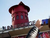 People take pictures of the landmark red windmill atop the Moulin Rouge, Paris' most famous cabaret club, after its sails fell off during the night in Paris, France, April 25, 2024.