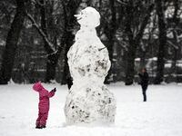 A child looks at a giant snowman as they stand in a snow-covered Victoria Park in Glasgow on February 9, 2021.