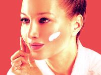 A woman applies a cleaning balm on her cheeks.