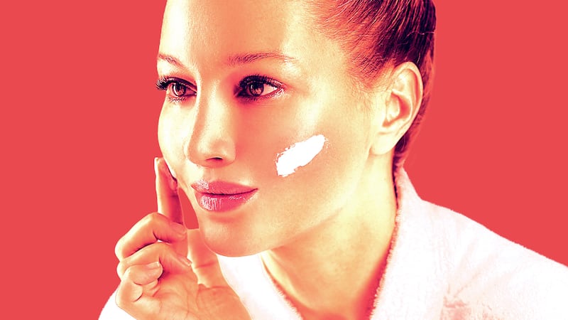 A woman applies a cleaning balm on her cheeks.