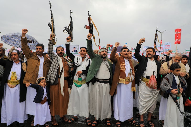 People lift rifles and placards as they chant during an anti-Israel and anti-US rally in the Huthi-controlled capital Sanaa on January 19, 2024,