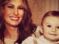 Melania Trump smiles as she holds an infant-aged Barron Trump, her now-18-year-old son.